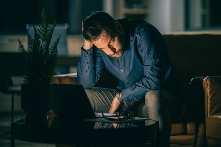 Mężczyzna siedzi z pochyloną głową, trzyma się za głowę – symbol stresu, przygnębienia i bezradności wobec decyzji urzędowej.